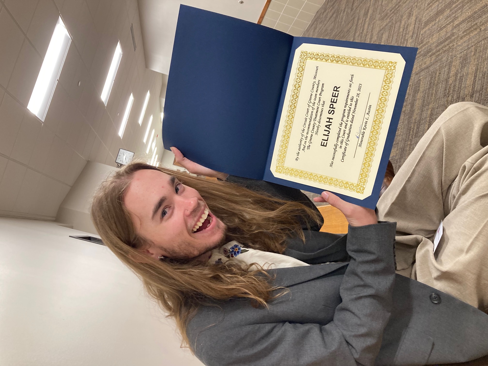 Elijah Speer shows off his treatment court certificate in the hallway outside the courtroom.