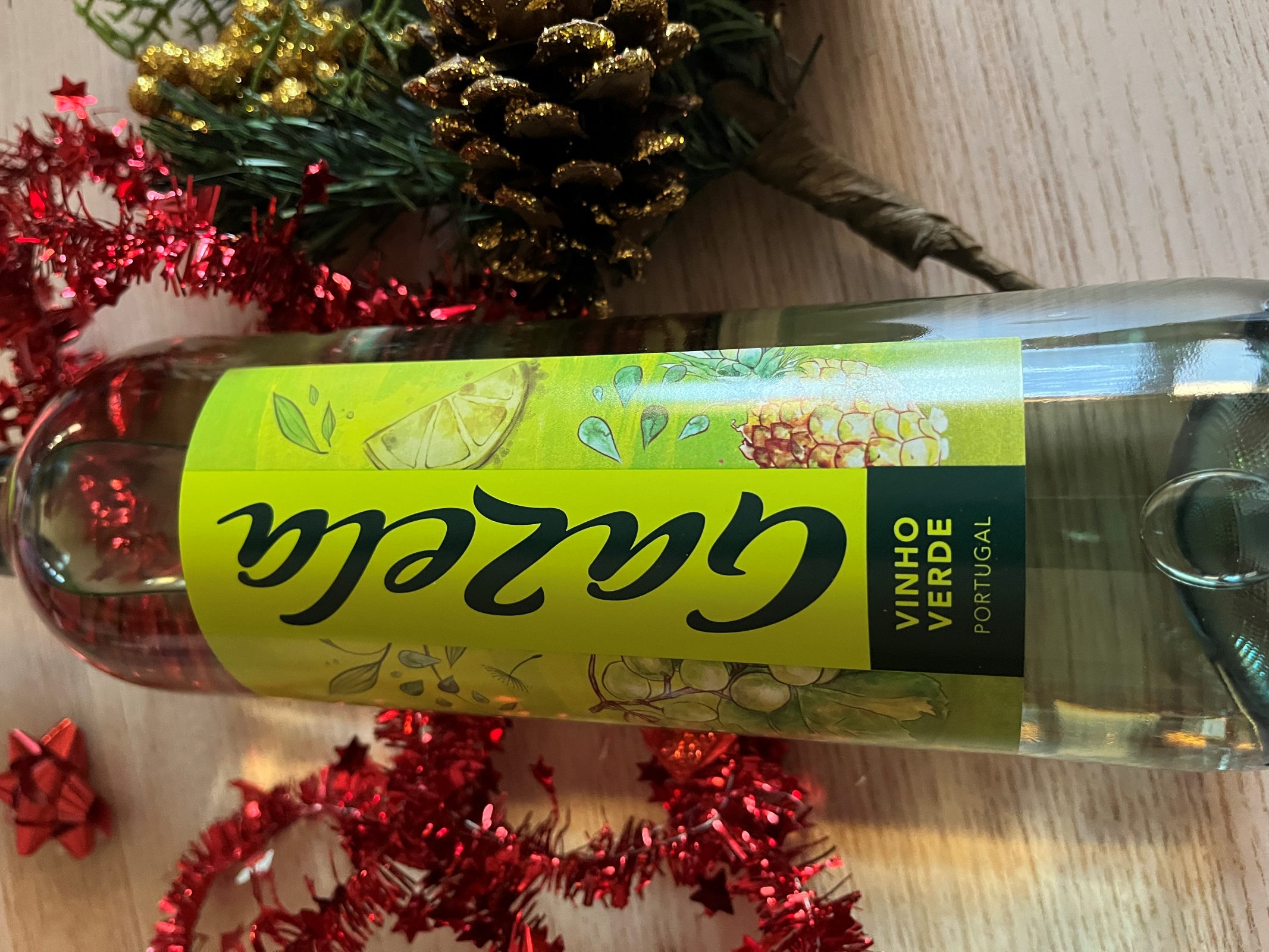 A bottle of Gazela Vinho Verde wine from Portugal lays on a table next to holiday decor