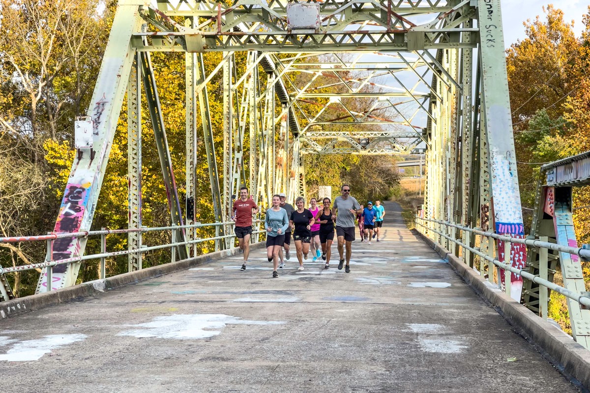 A group of people runs across the iron bridge over the James River