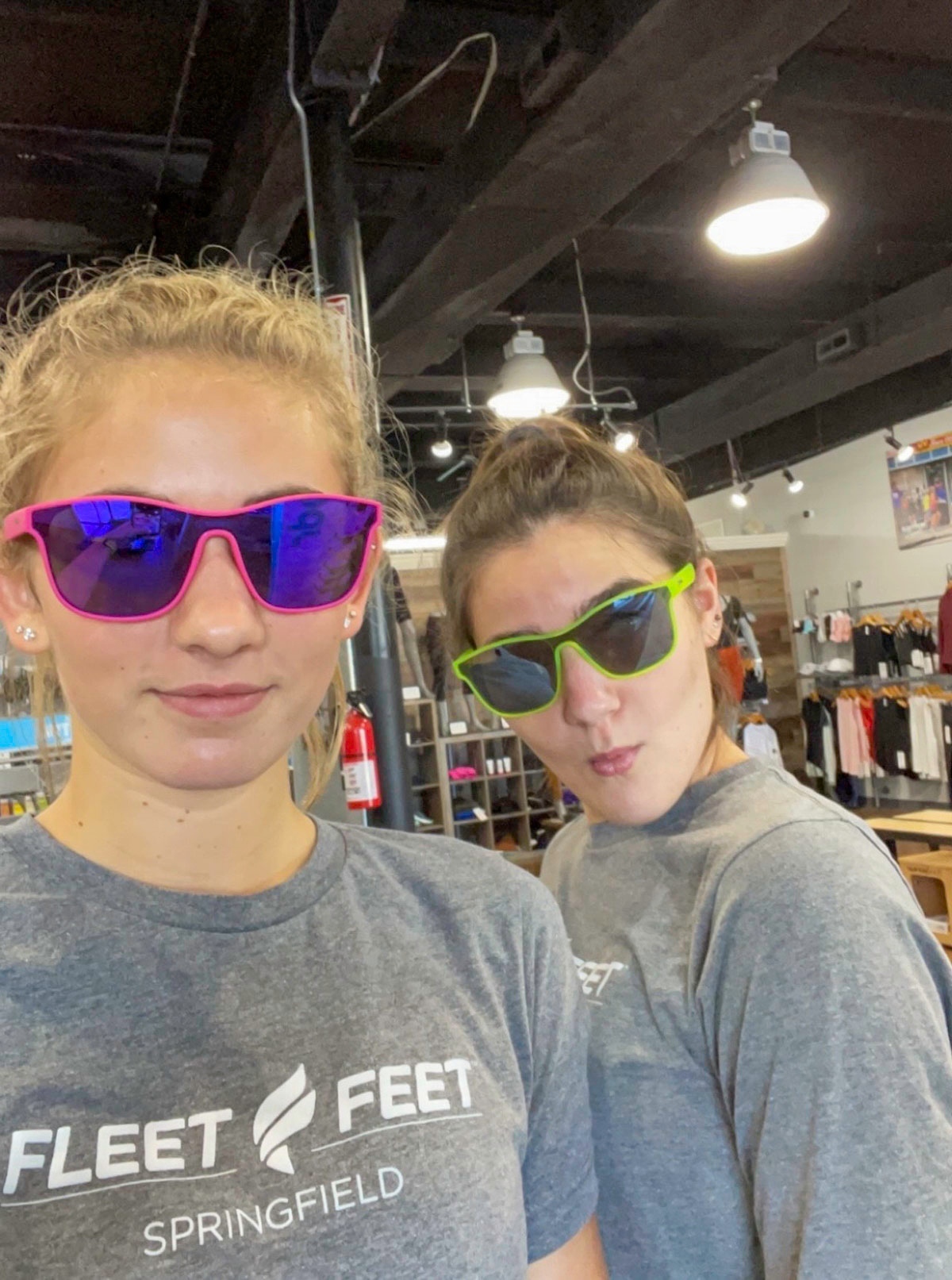 Two women model sunglasses while wearing gray Fleet Feet T-shirts