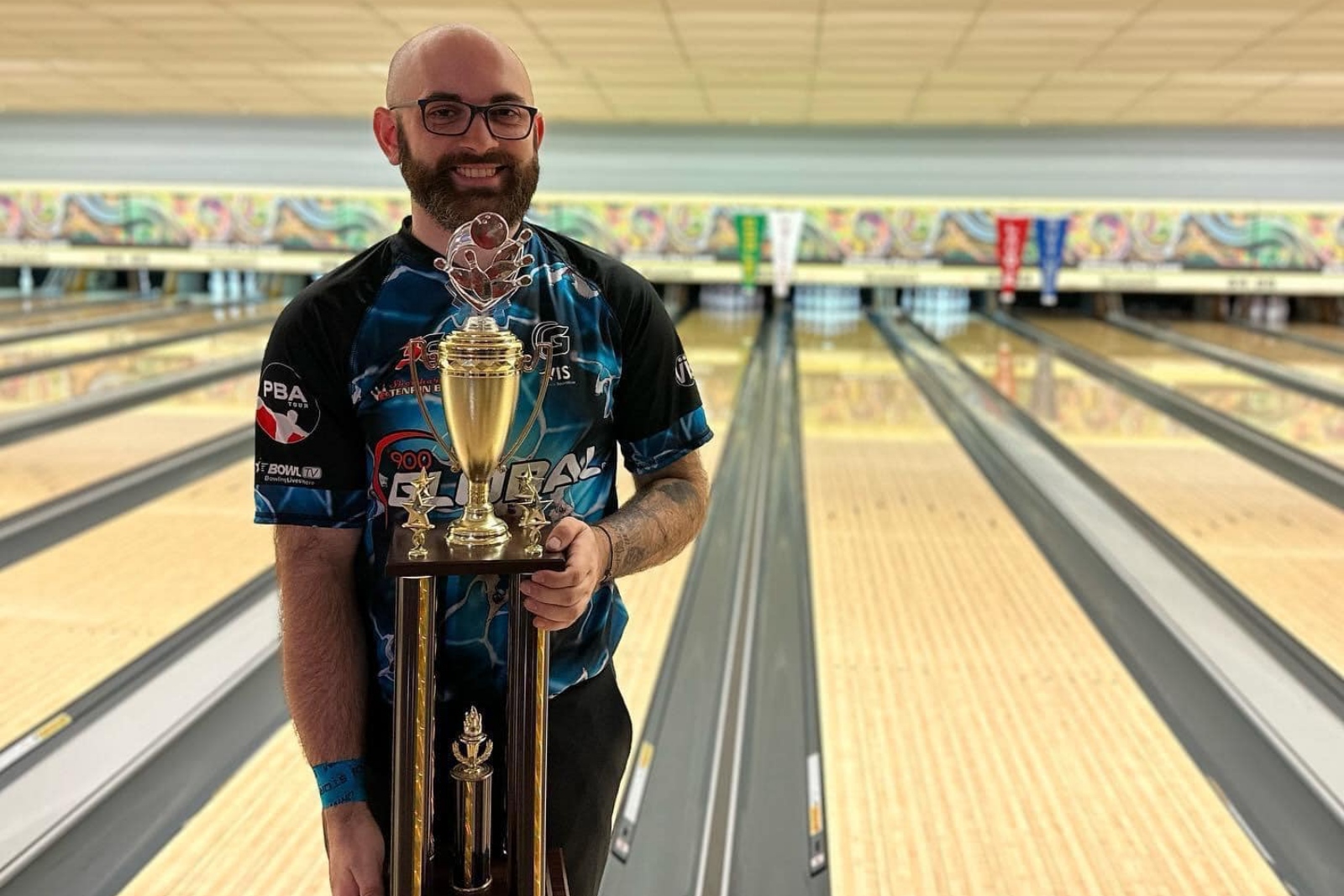 Sam Cooley holds a trophy while standing next to bowling lanes