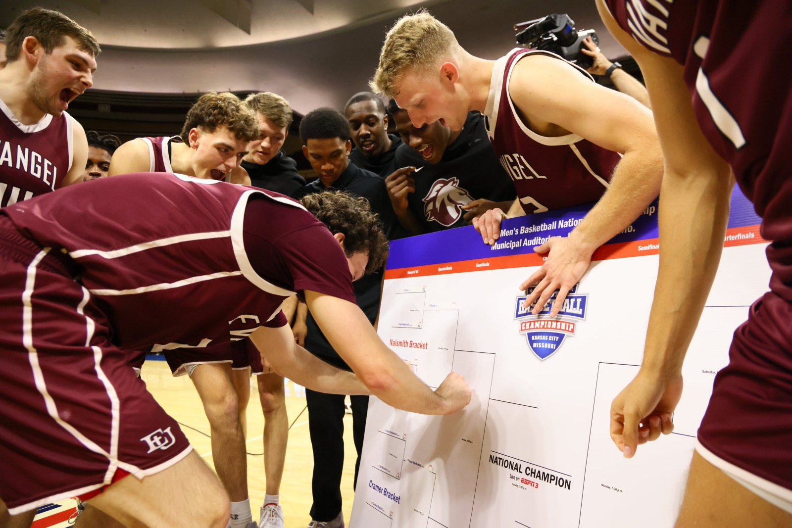 Evangel players stick their team’s name on the NAIA bracket round of eight following the victory over Lewis-Clark. (Photo by Evangel University Athletics)