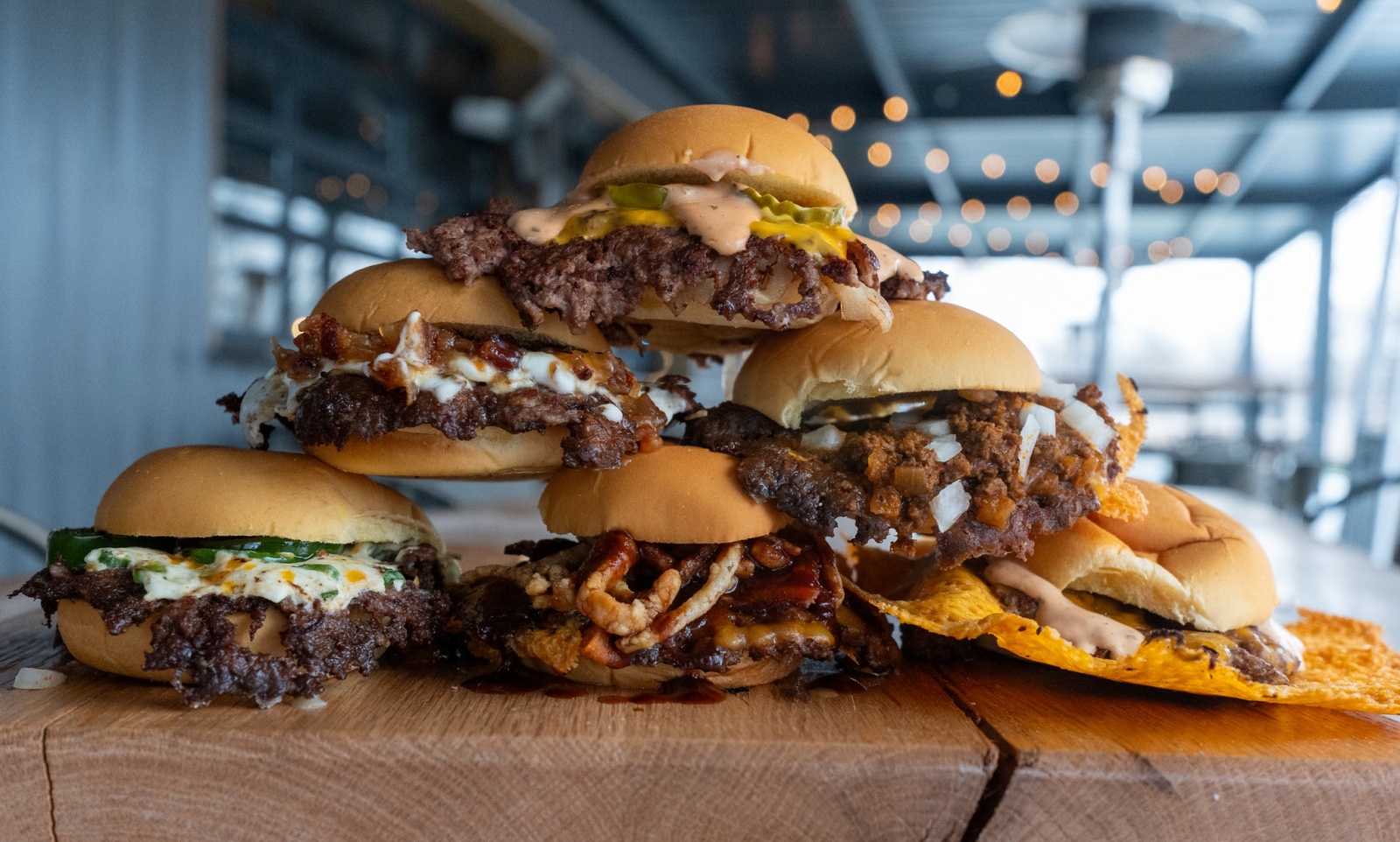 Six hamburgers from Mo Slider Company are stacked into a pyramid on a table