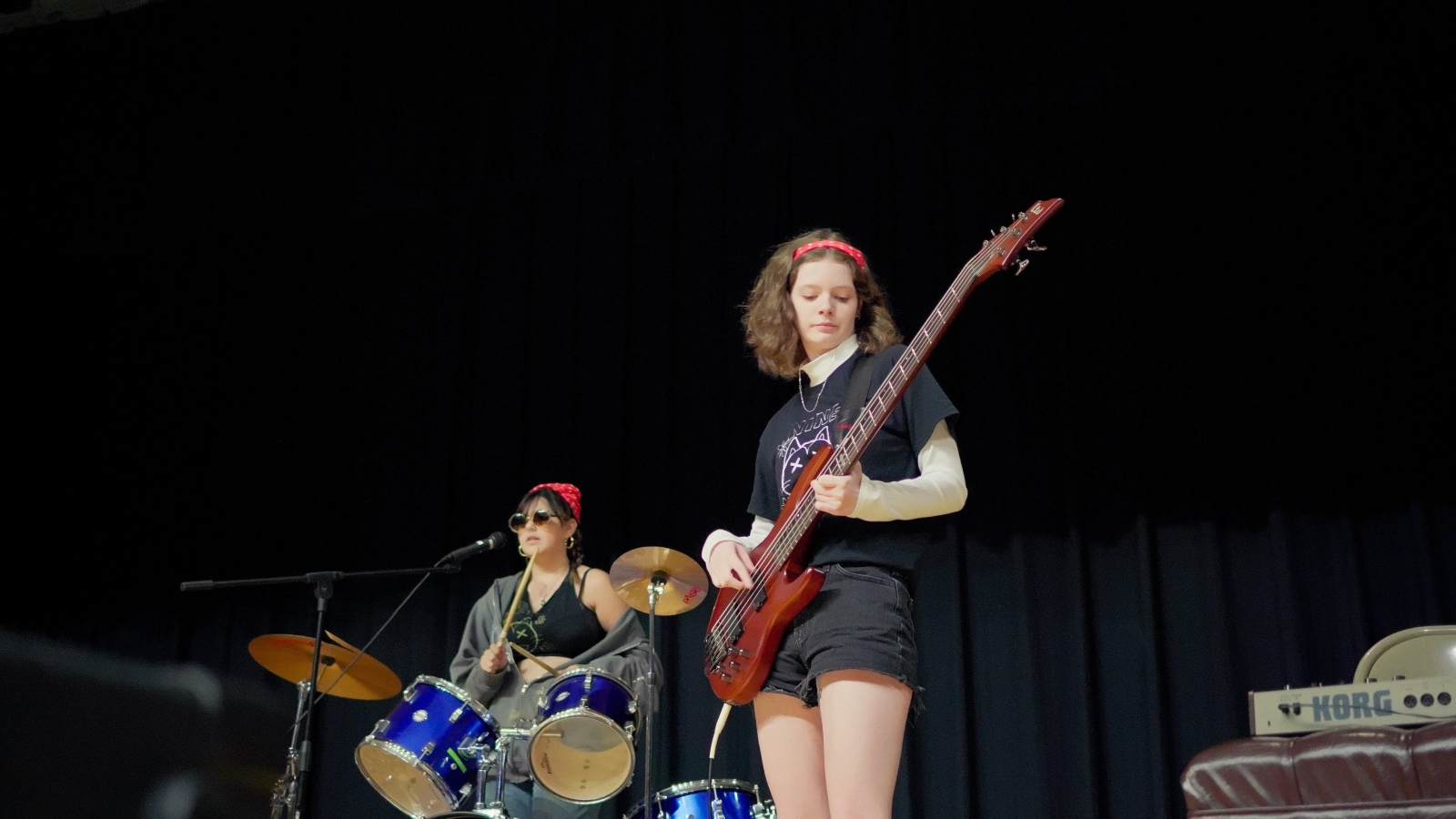 A bass player and drummer perform on stage at Queen City Rock Camp