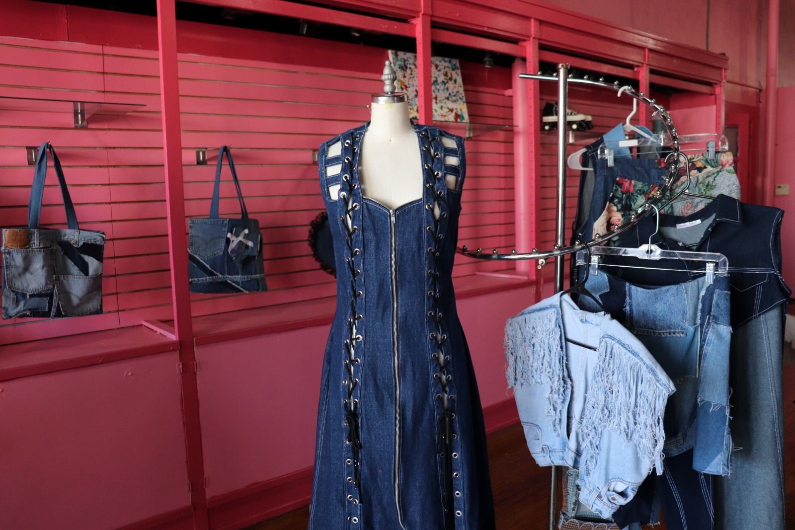 A denim dress in a boutique with pink walls and shelves