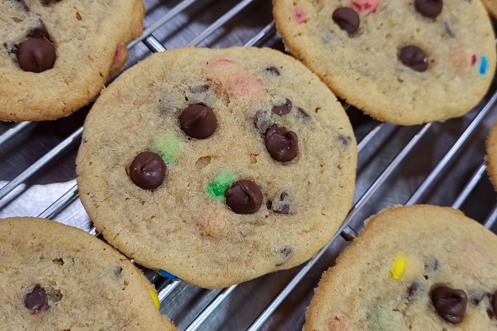 Chocolate chip and M&M cookies rest on a cooling rack