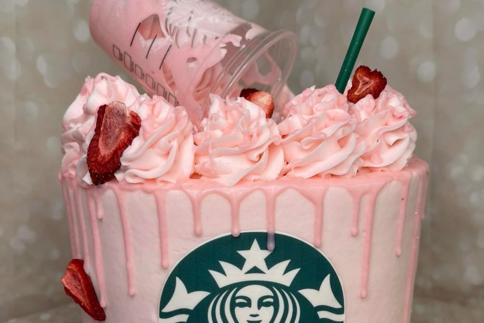 A pink cake decorated with a Starbucks logo and strawberries