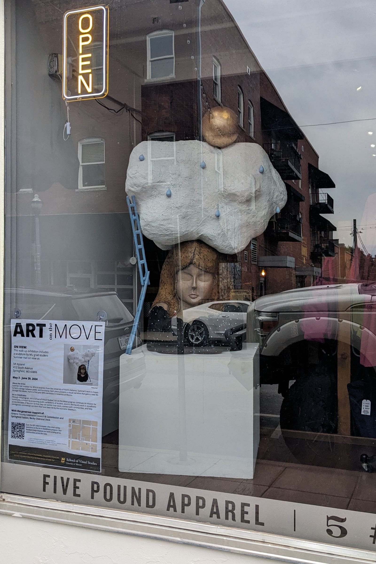 A sculpture of a woman with a cloud on her head is on display in the front window of 5 Pound Apparel in downtown Springfield, Missouri.