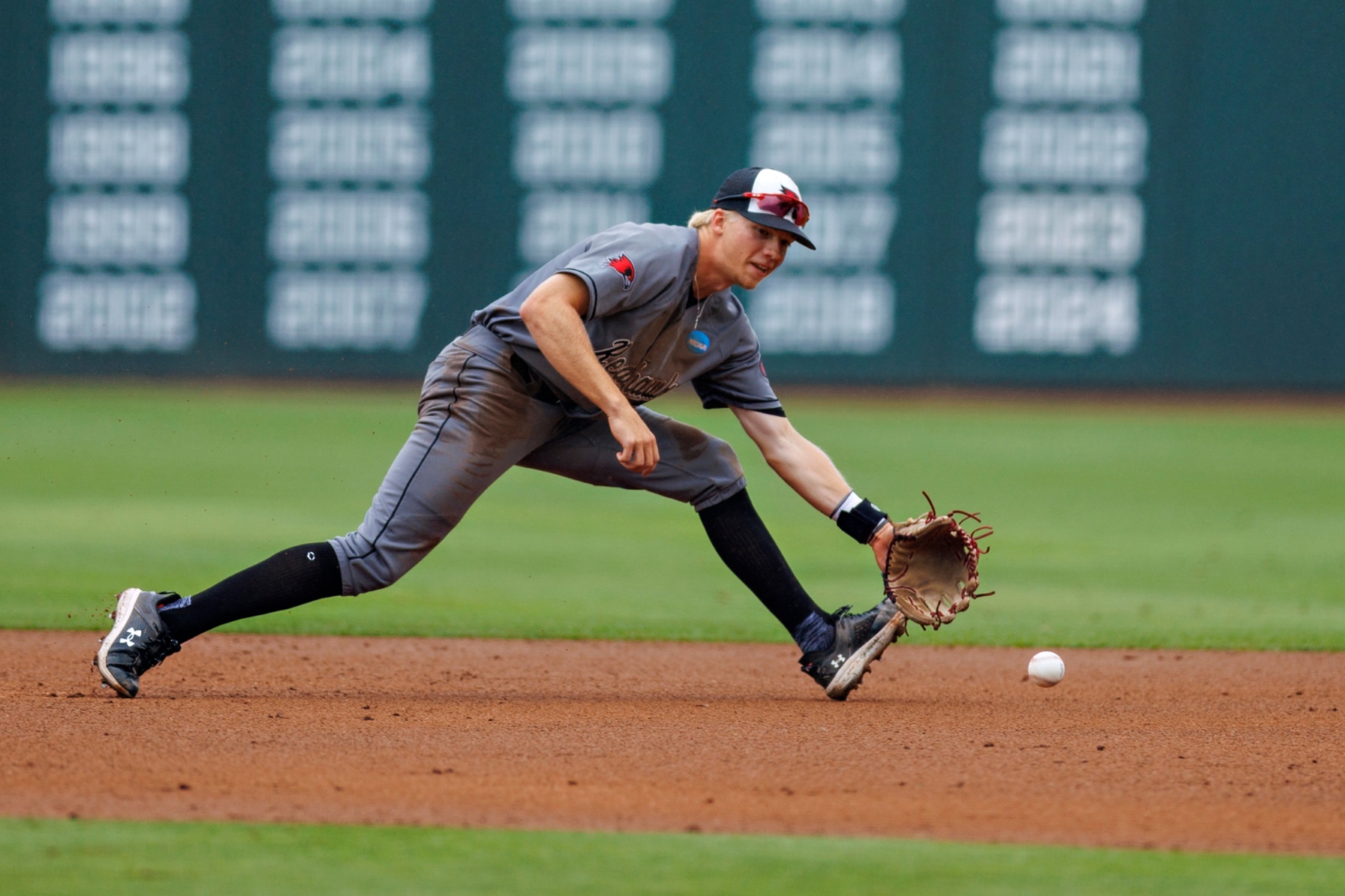 Brooks Kettering, wearing a Southeast Missouri State baseball uniform, stretches to his left to catch a ground ball during a baseball game at Baum-Walker Stadium in Fayetteville, Arkansas.